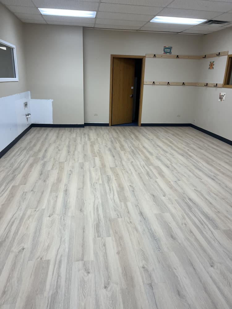 Light gray-oak luxury vinyl plank flooring in an empty commercial classroom