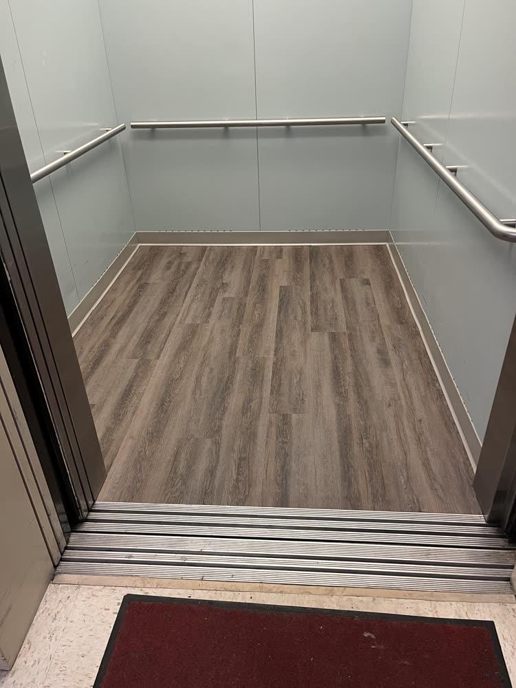 New luxury vinyl plank flooring installed inside a commercial elevator cab