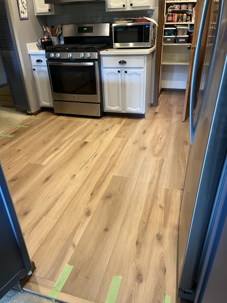 Light oak laminate flooring installed in a kitchen with white cabinets