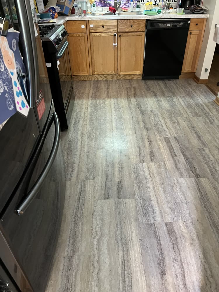 Gray stone-look vinyl plank flooring in a kitchen with oak cabinets